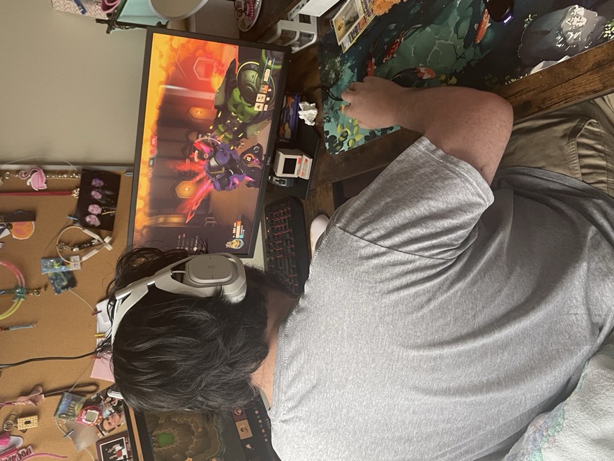 Adam at a desk gaming, headphones on, back to the camera