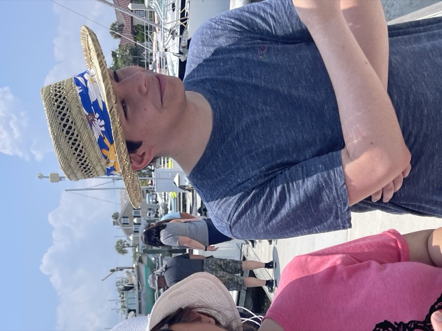 Eric at a marina wearing a straw hat, looking off camera