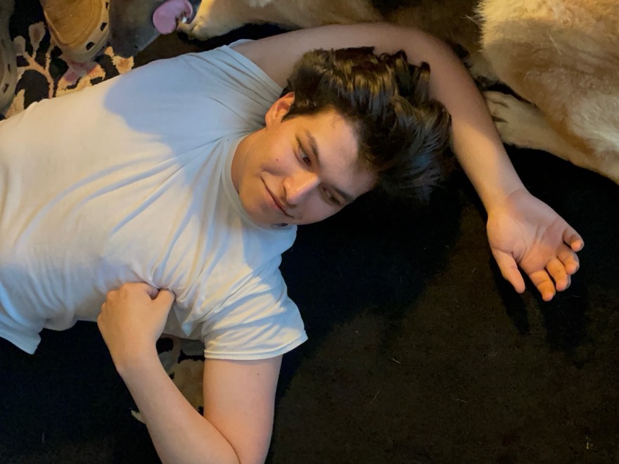 Eric lying on the floor next to a large dog