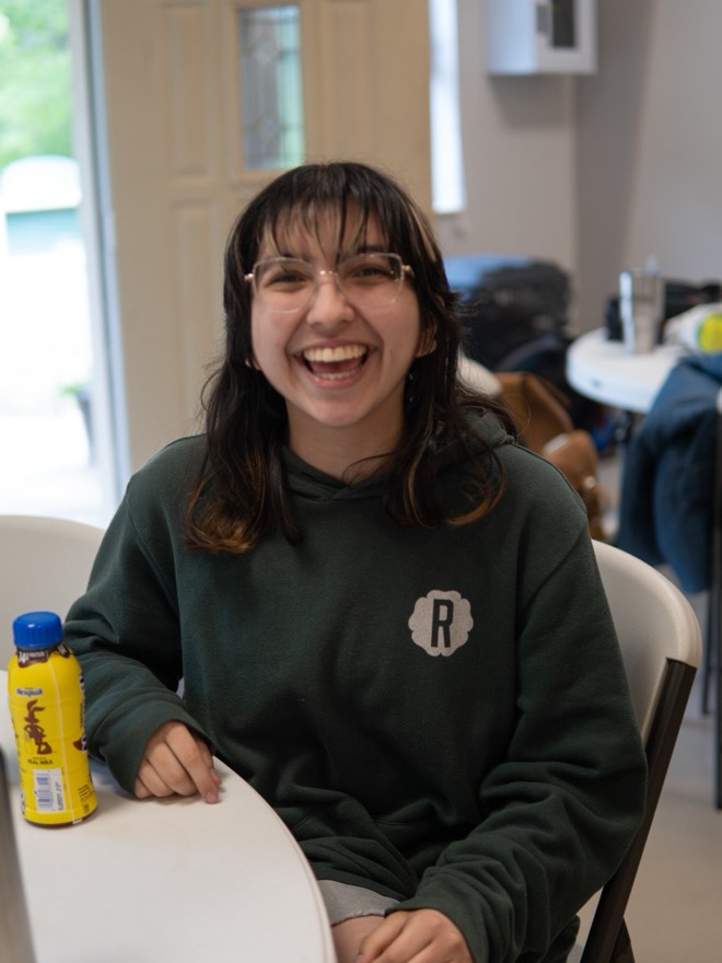 Megan laughing at a table in a green hoodie