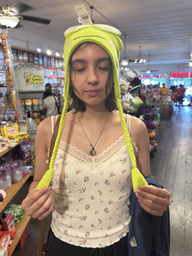 Megan trying on a bright green frog hat in a shop