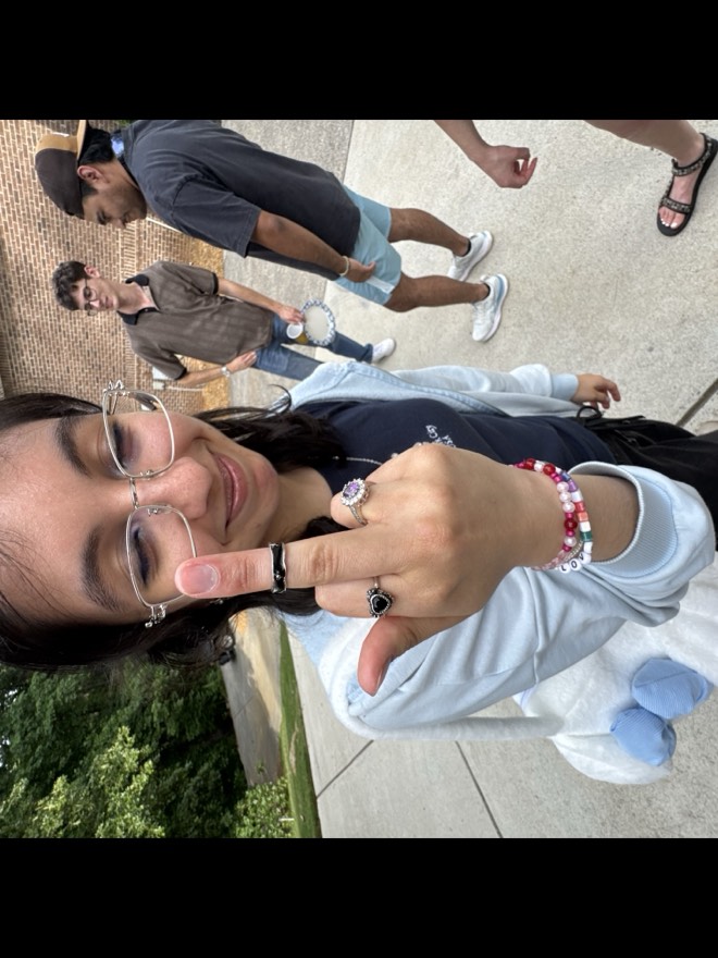Megan holding a ringed hand close to the camera with a deadpan expression